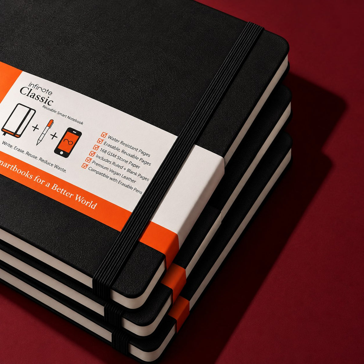 Three black Infinote Classic notebooks stacked on a burgundy ground